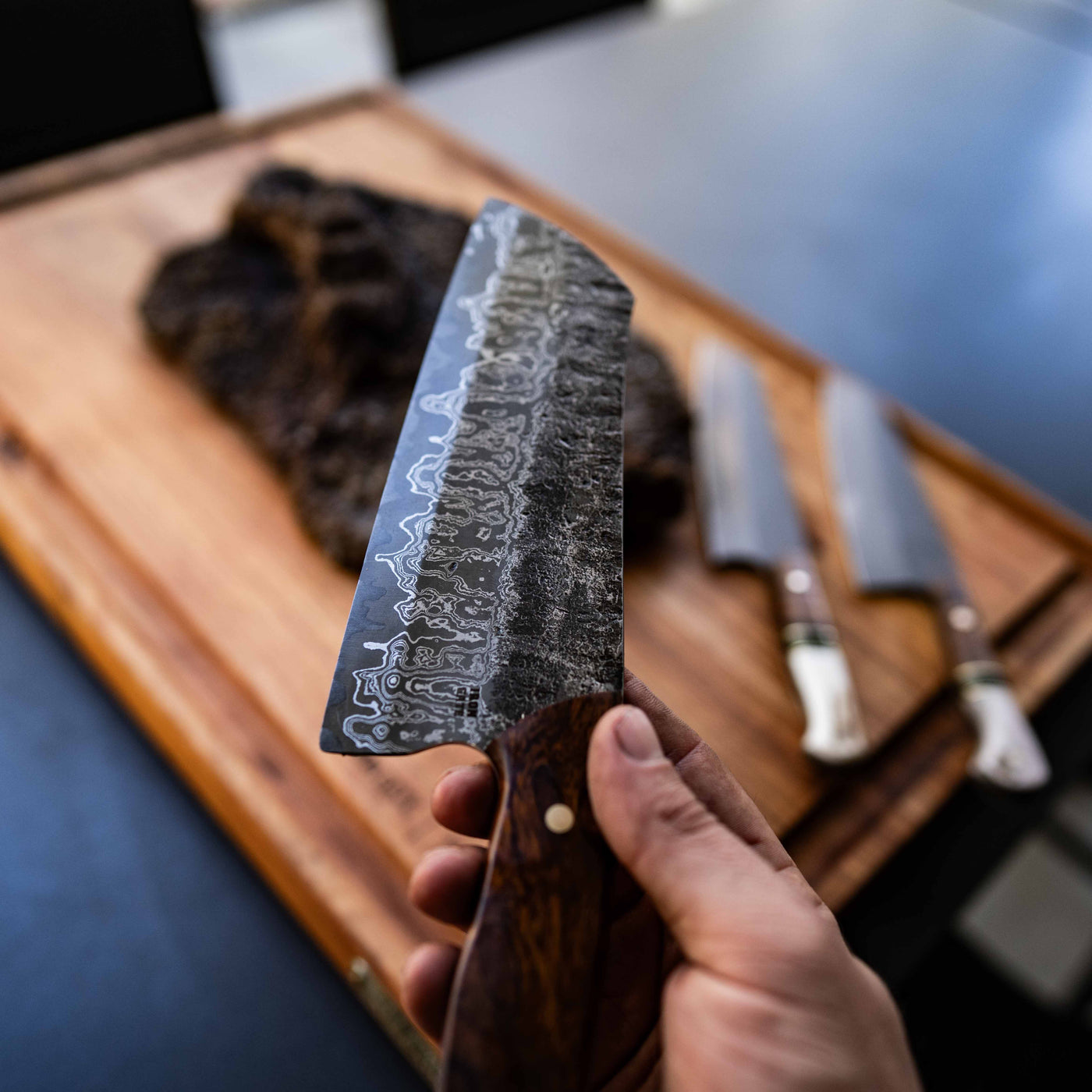 Six handmade Iron Gate knives with deer antler and timber handles laid on black leather