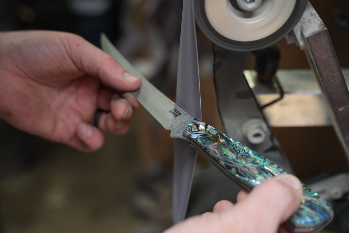 Hand-finishing an abalone handle on the grinder