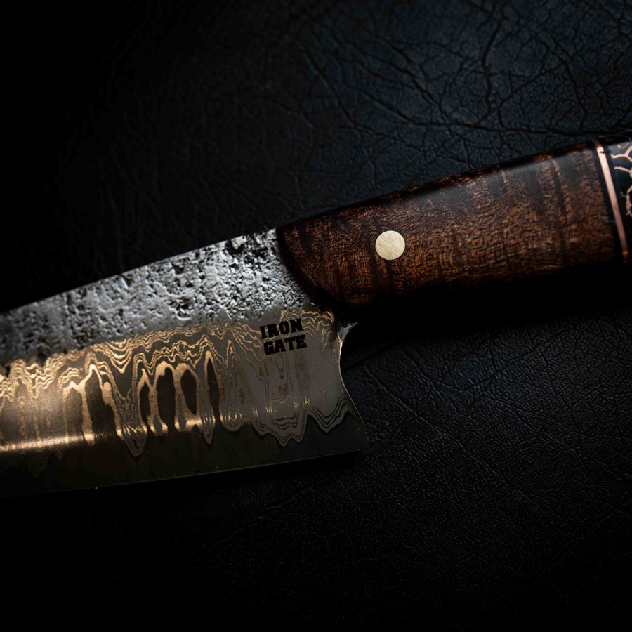 Macro of a damascus steel pattern with the Iron Gate maker's mark stamped near the handle