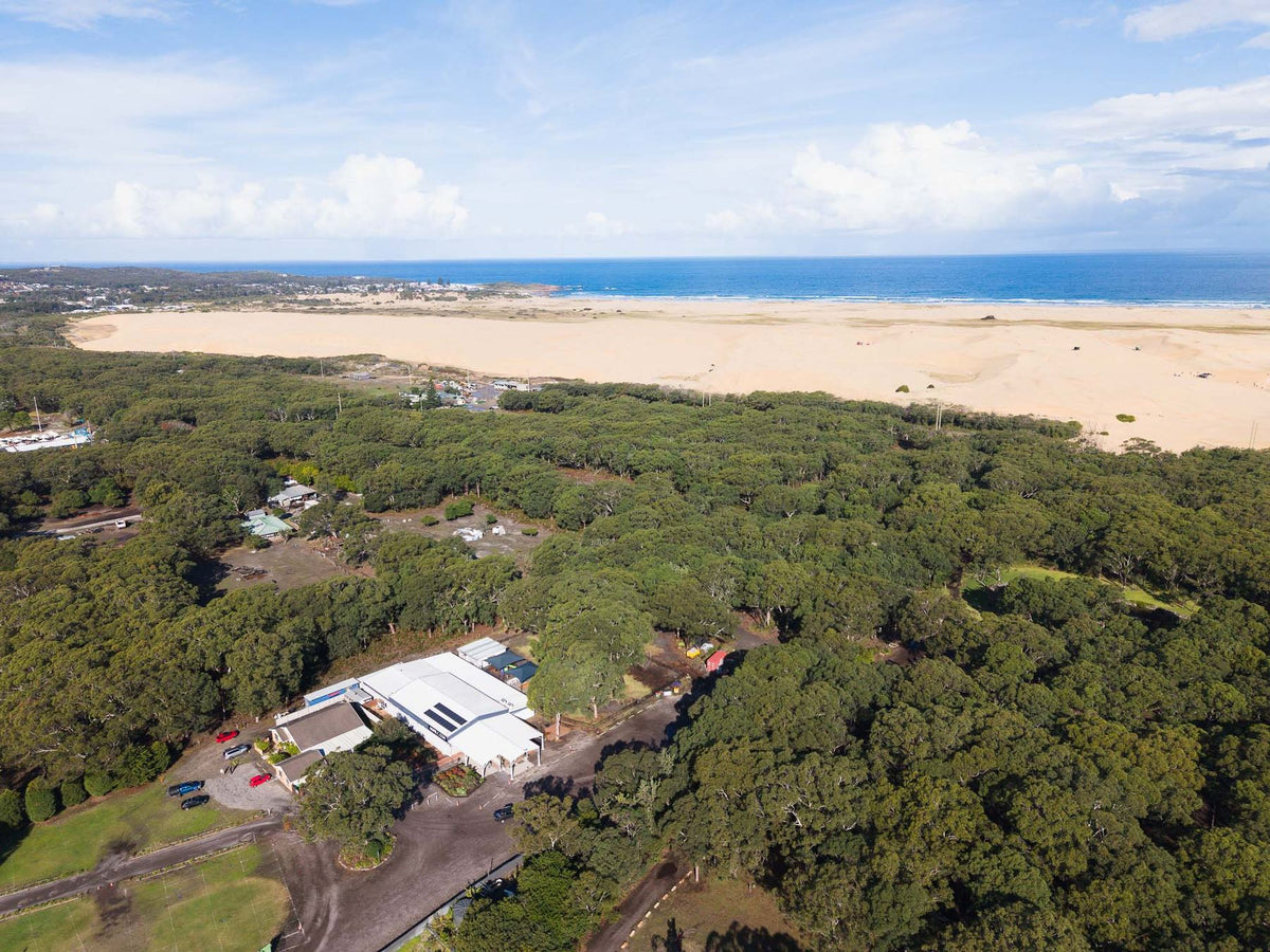 Aerial view of coastal bushland, a long beach and sand dunes at Anna Bay