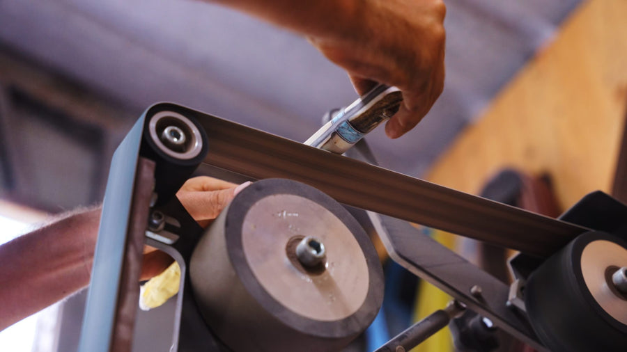 Hands guiding steel on a belt grinder
