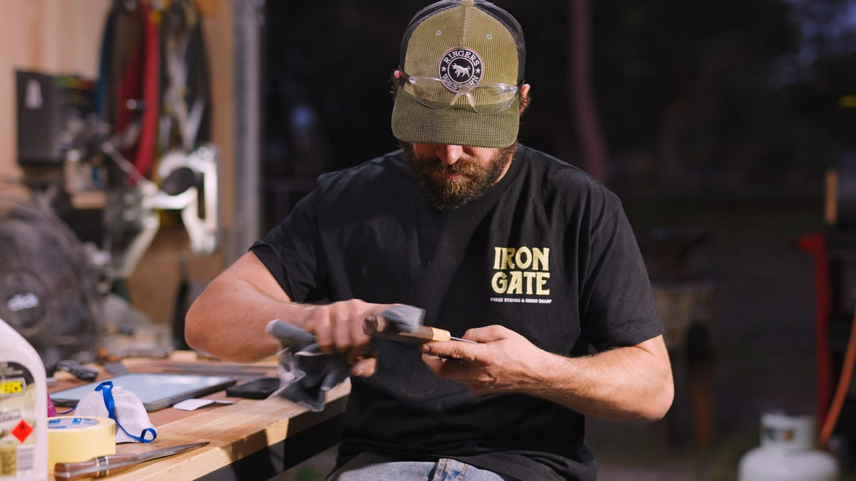 A maker in a cap works on a handle at his workbench